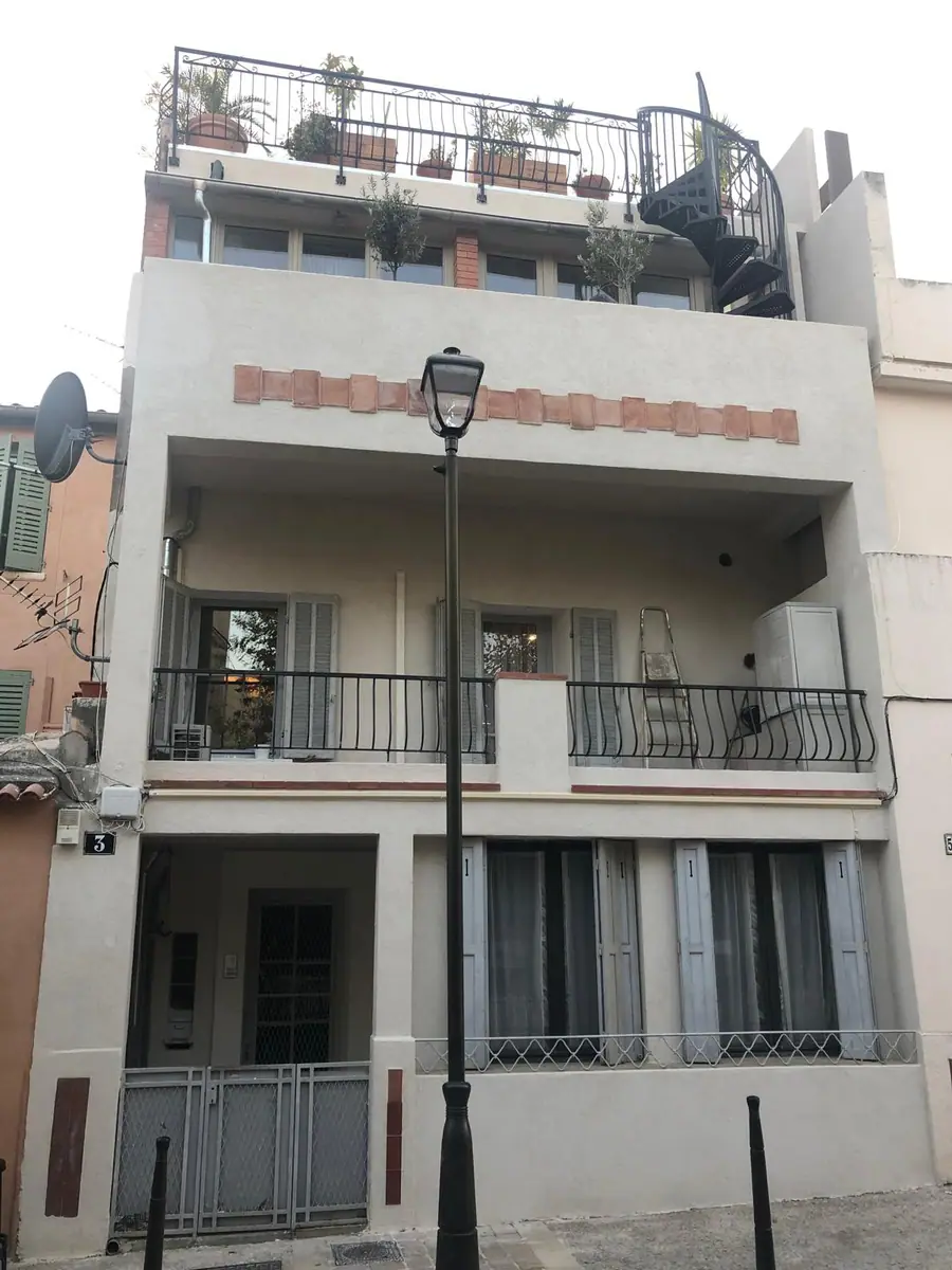 La même façade après ravalement, enduit uniforme et bandeau de briques restitué — Castagne Couverture