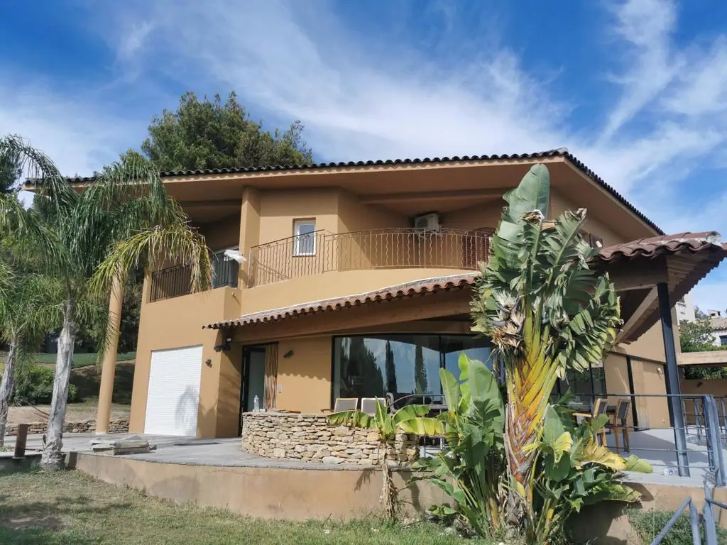 Villa ravalée en enduit taloché ocre, débord de toit sur charpente apparente